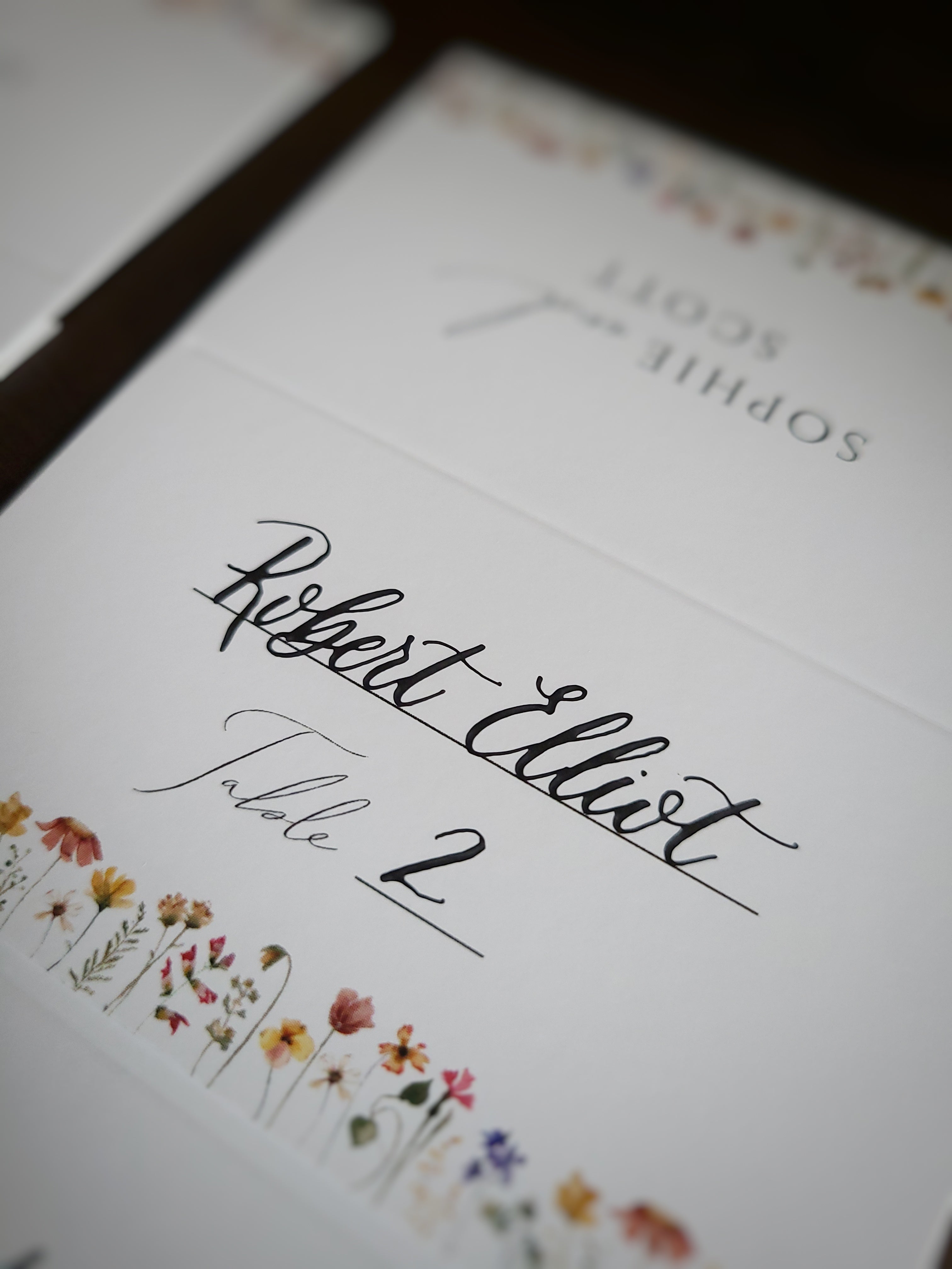 close up image of calligraphy escort card with guest name and table number